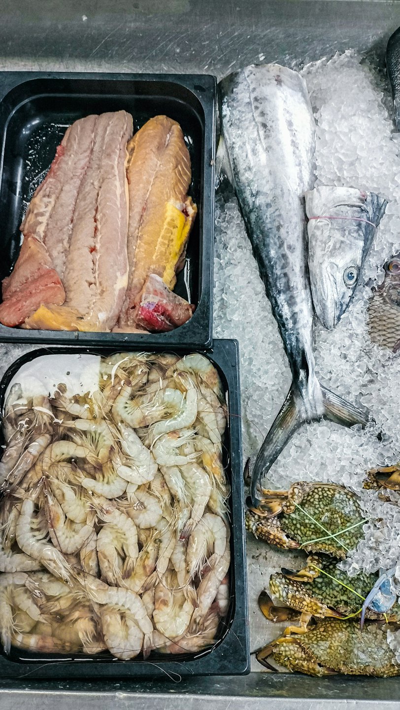 Pesce fresco e gamberi esposti su un letto di ghiaccio.