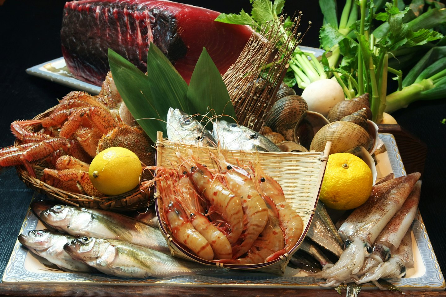 Un'abbondante selezione di pesce fresco e verdure disposti su vassoi.