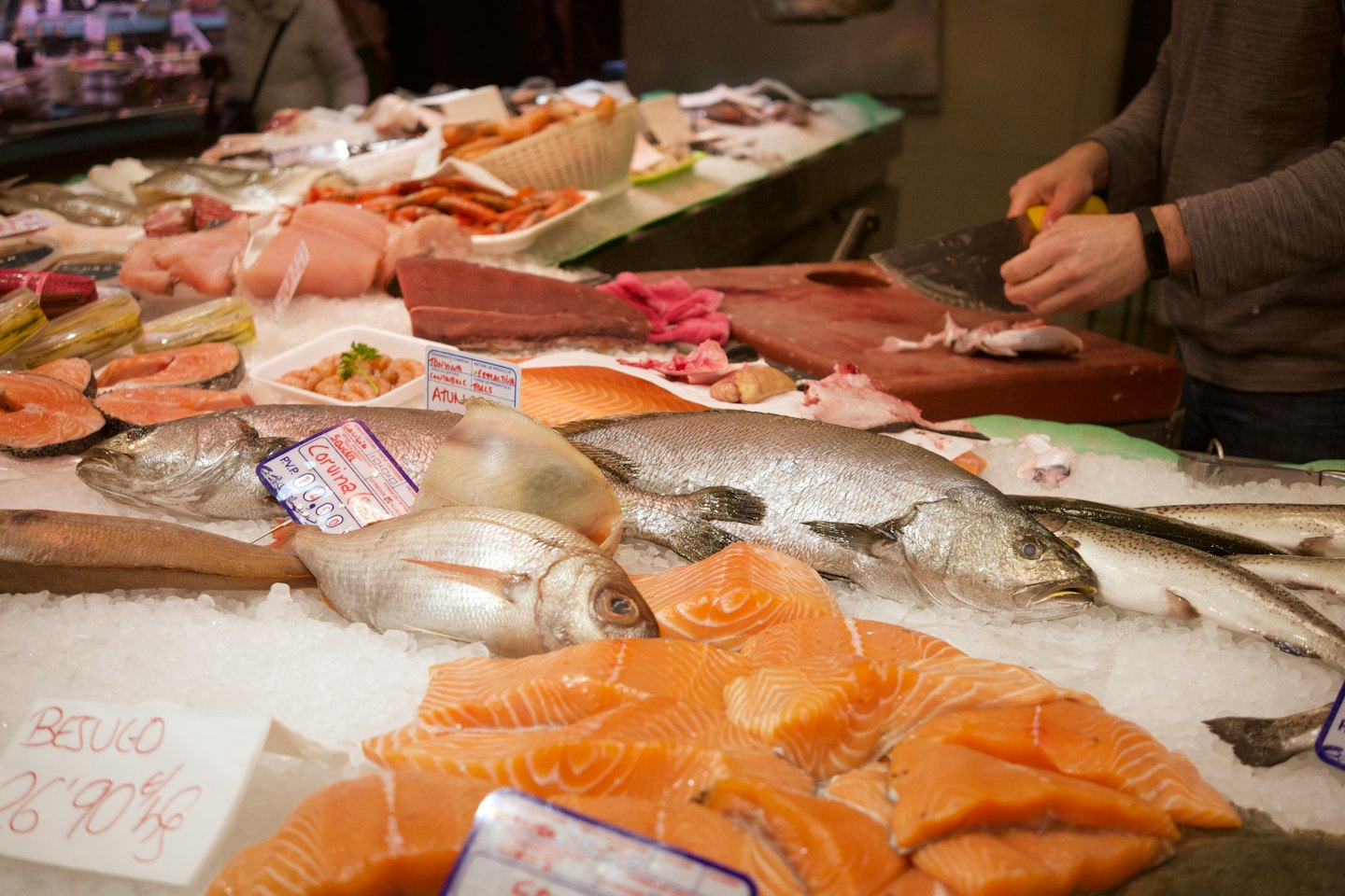 Pescatore prepara pesce fresco sul ghiaccio al banco del mercato.